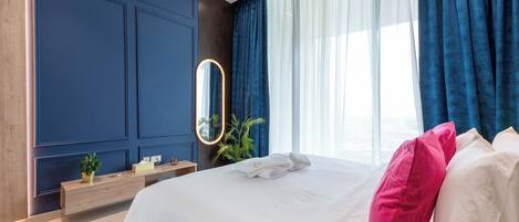 A hotel room with a large bed, a bedside table, a mirror, and a window with curtains.
