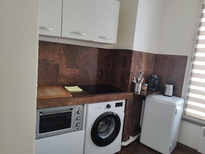 A compact kitchen with a built-in oven, a washing machine, and a coffee maker. - Beautiful T2 de la Poste Drancy (Drancy)
