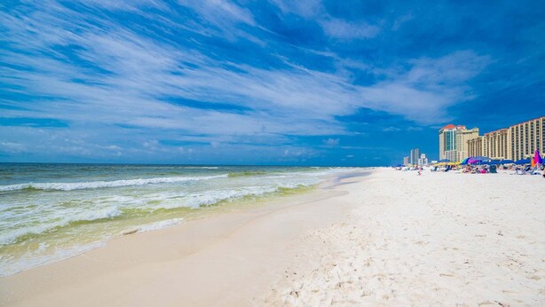 Een strand met een hotel op de achtergrond.