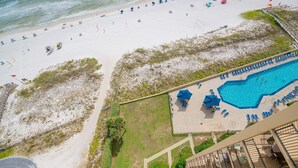 A beach with a swimming pool, umbrellas, and lounge chairs. - Phoenix V 1516 2 Bedroom Condo (Orange Beach)