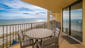 Ein Balkon mit Blick auf das Meer, ein runder Tisch und vier Stühle.