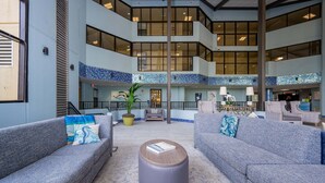 A spacious lobby with grey sofas, a round coffee table, and a tiled floor. - Phoenix V 1110 2 Bedroom Condo (Orange Beach)