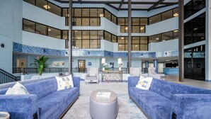 A spacious lobby with blue sofas, a central coffee table, and a tiled floor. - Phoenix V 1110 2 Bedroom Condo (Orange Beach)