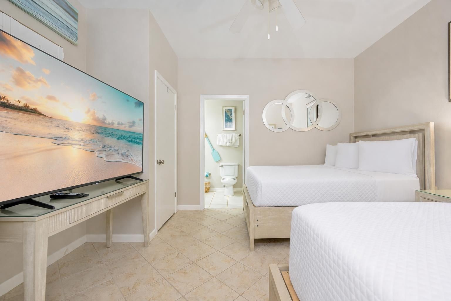 Ein Hotelzimmer mit Bett, Schreibtisch mit Fernseher und einem durchgegangenen Tür erkennbaren Badezimmer.
