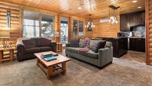 A log cabin interior with a living room, kitchen, and large windows. - Deer Valley Condo Near Base Hot Tub (Park City)