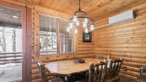 A wooden interior with a dining table, chairs, a chandelier, and a window with blinds. - Deer Valley Condo Near Base Hot Tub (Park City)