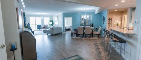 A spacious living area with a dining table, bar stools, and a kitchen area.