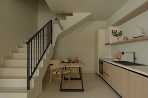Une cuisine moderne avec un coin repas, un escalier en bois et des placards intégrés.