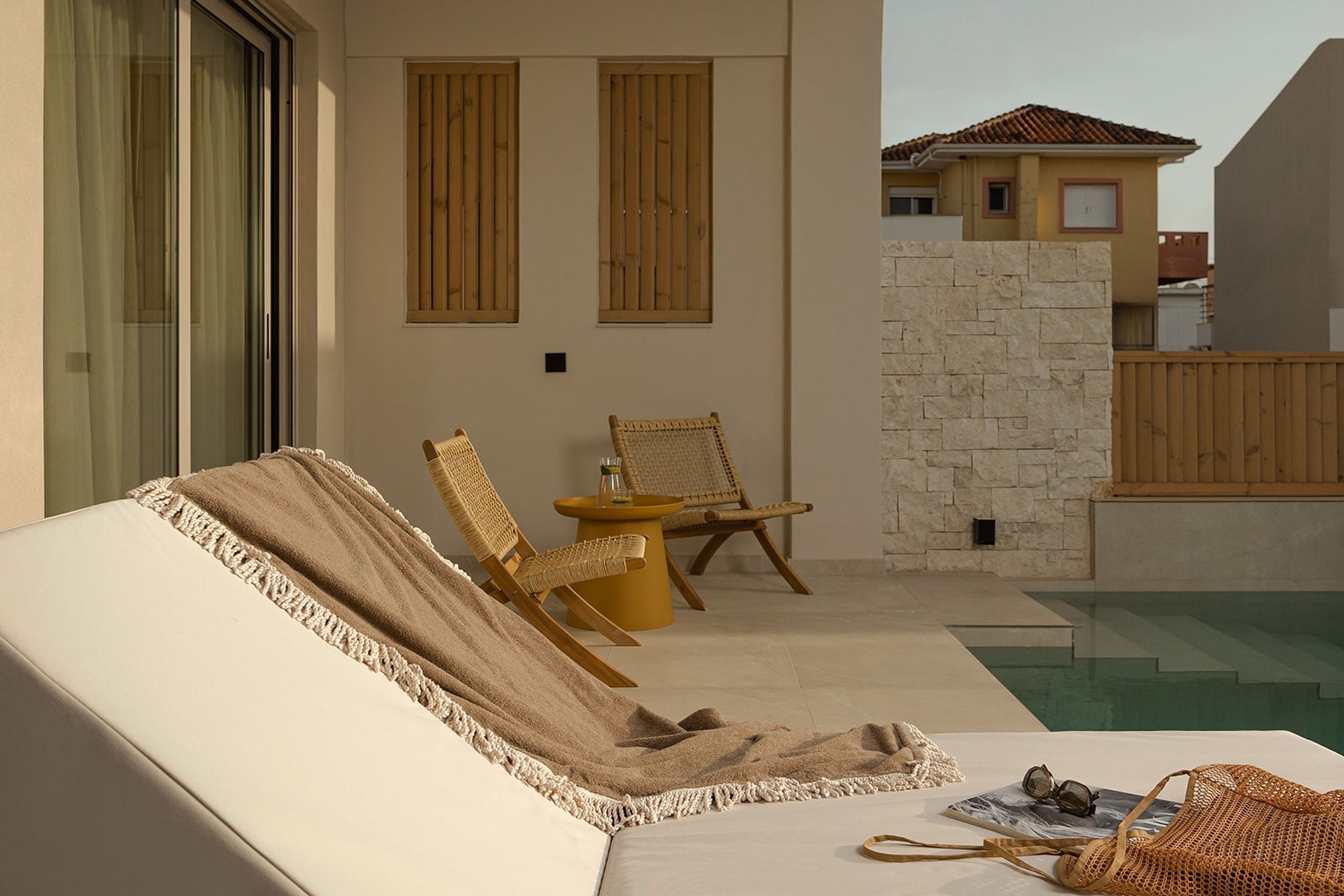 Un espace extérieur ensoleillé, aménagé avec des meubles de jardin, une piscine, des chaises en osier et un fauteuil de relaxation.