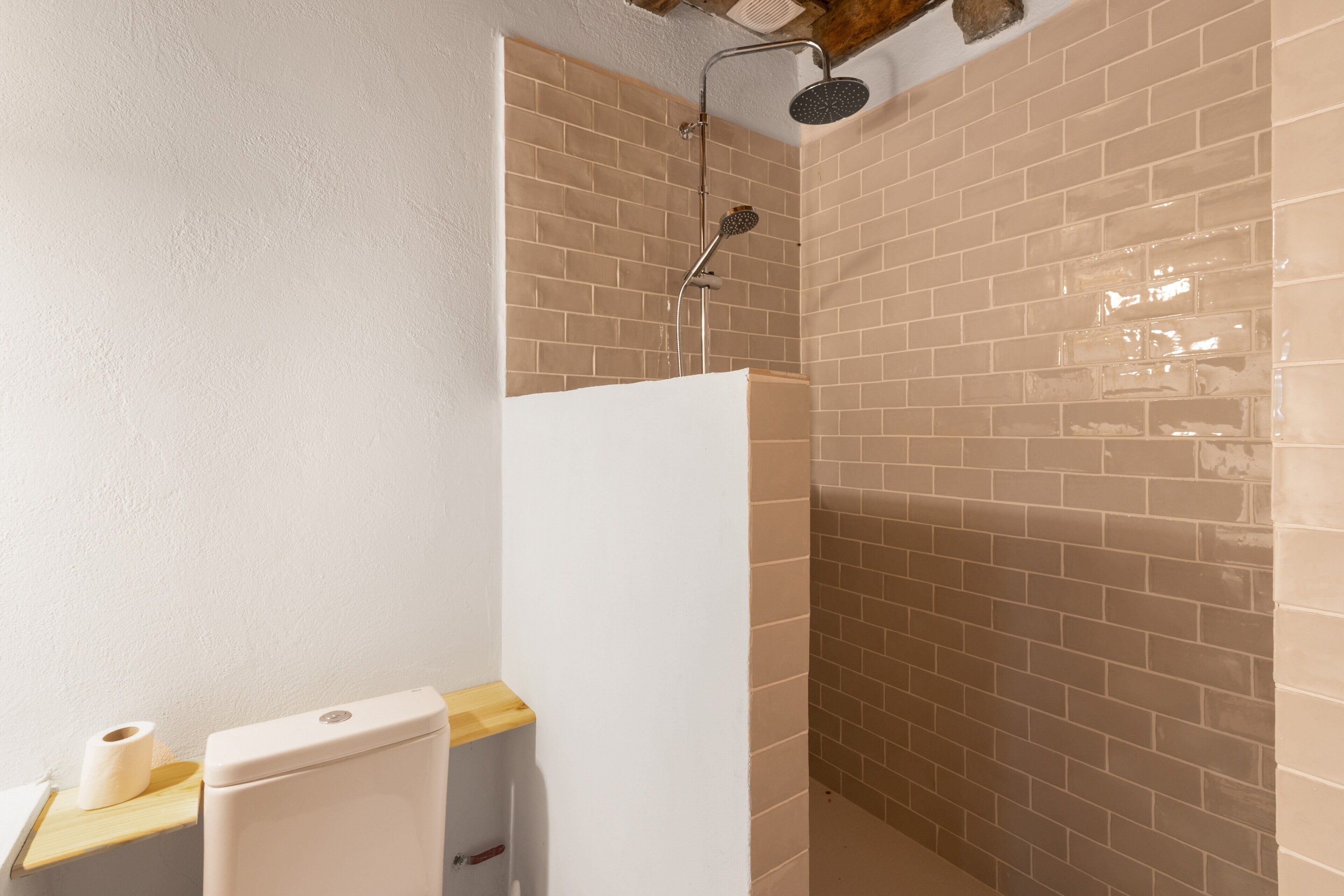 Un baño con ducha, inodoro y repisa de madera.