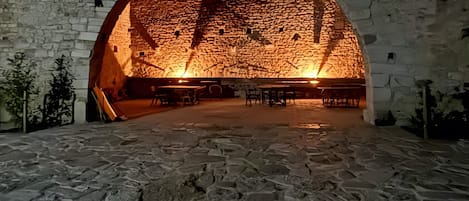 An arched stone structure with a seating area inside, surrounded by stone walls.
