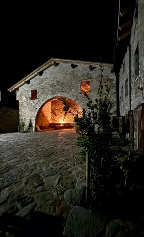 Un bâtiment en pierre doté d’une entrée en arc de cercle, d’un petit jardin et d’une porte en bois rustique.