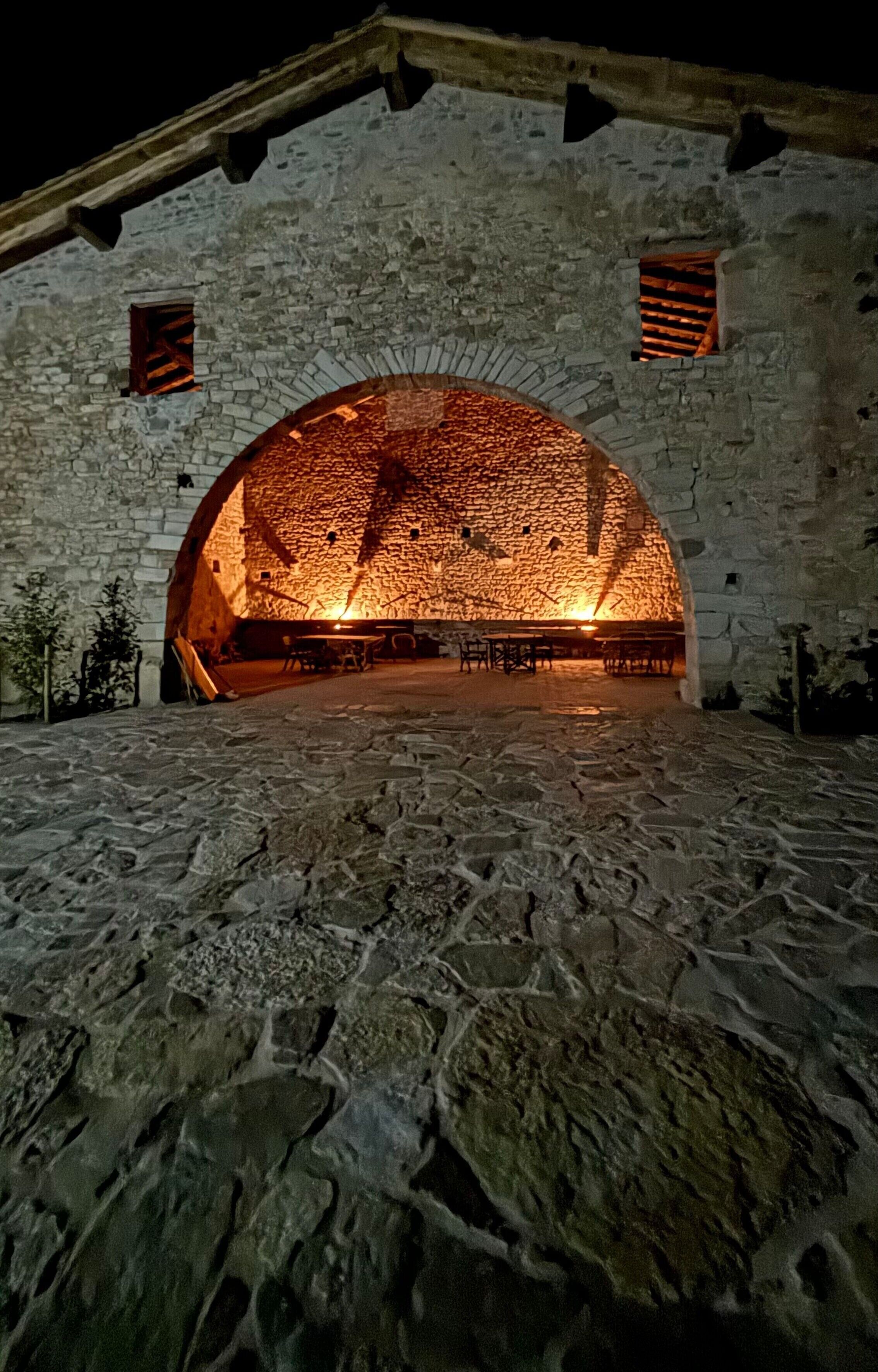Un bâtiment en pierre doté d’une entrée en arc de cercle, d’un sol en pierre et d’une petite fenêtre avec des volets.