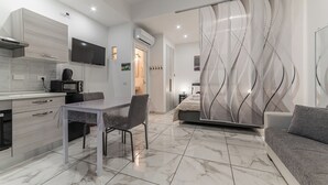 A modern kitchen with a dining table and chairs, a sofa, and a bedroom with a bed and curtains. - Rome in Love Caffarella - Metro P. Lungo (Rome)
