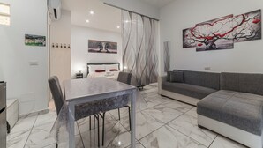 A modern living room with a dining table, sofa, and artwork on the walls. - Rome in Love Caffarella - Metro P. Lungo (Rome)