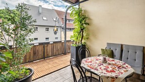 Ein Balkon mit Tisch, Stühlen und Topfpflanzen.