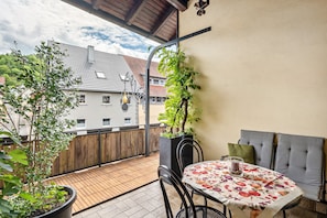 A balcony with a table, chairs, and potted plants. - Vacation at the Winery – Apartment "Kleine Galerie" (Königheim)