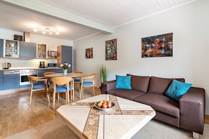 Una sala de estar moderna con un sofá marrón, una mesa de centro y un comedor con una mesa y sillas de madera.
