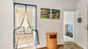 Ein Zimmer mit einer Schiebetür, einem Holztisch und zwei abstrakten Bildern an der Wand.