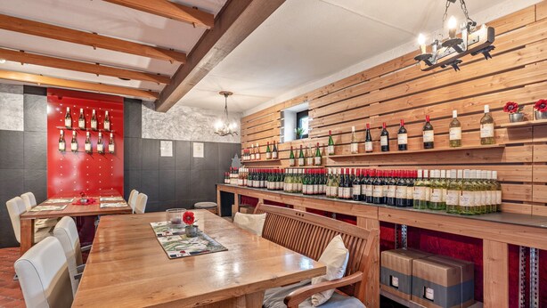 Ein Restaurant mit Holztisch, Stühlen und einer Weinwand.