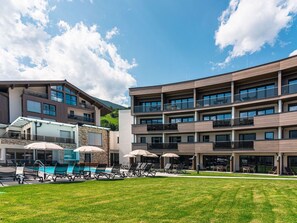 A modern hotel with a pool area, outdoor seating, and a view of the mountains. - 3_SPA - Comfort Studio 102 by Interhome (Zell am See)