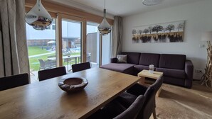 Un coin repas avec une table et des chaises en bois, un canapé et un tableau accroché au mur.