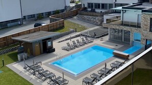 Une piscine avec des chaises longues, un bâtiment en pierre et une église dotée d’un clocher.
