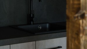Eine Küche mit modernem Wasserhahn, grauen Schränken und einer Holztür.