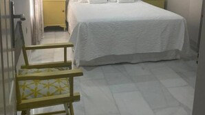 Een slaapkamer met een gestreept behang, een bed met witte beddengoed, een hoofdeinde met een wereldbol ontwerp, en een klein nachtkastje.