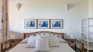 A bed with white linens, a wooden headboard, and three framed pictures of a lighthouse on the wall. - Villa Simonetta with Sea View, Wi-Fi, and Air Conditioning (Costa Rei)