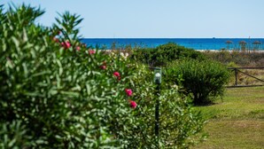 A coastal landscape with a clear view of the sea, a beach with umbrellas, and lush greenery. - Villa Simonetta with Sea View, Wi-Fi, and Air Conditioning (Costa Rei)