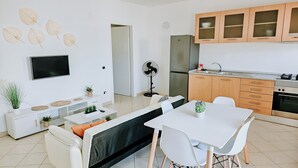 Uma cozinha moderna com armários brancos, forno embutido e geladeira de aço inoxidável.