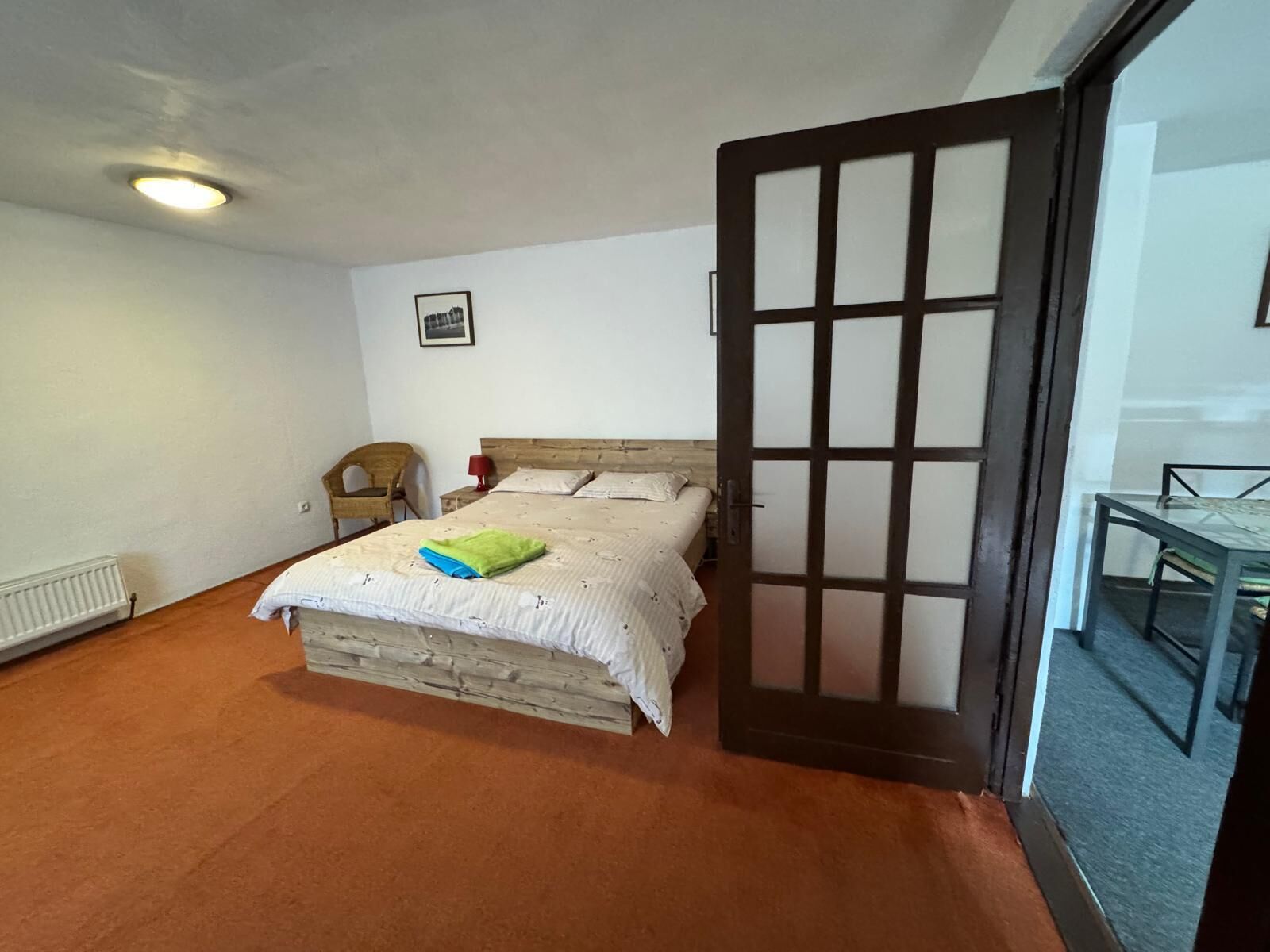 Ein Schlafzimmer mit einem Bett, einem Sessel, einem Tisch und einer Tür.