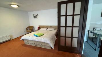 Ein Schlafzimmer mit einem Bett, einem Sessel, einem Tisch und einer Tür.