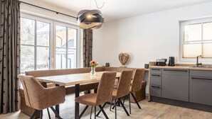 Una cocina moderna con comedor, que presenta una mesa de madera, sillas y una lámpara colgante.