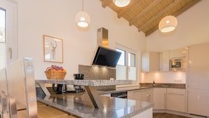 Cocina moderna con encimeras de granito, electrodomésticos de acero inoxidable e iluminación colgante.