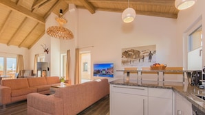 Un interior moderno con techo de madera, un sofá, una zona de comedor y una cocina.