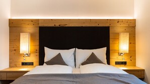 A bed with a dark headboard, two bedside lamps, and a grey blanket. - 3_SPA Deluxe Garden 417 by Interhome (Zell am See)