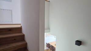 A staircase with wooden steps leading to a dining area with a table and chairs. - 3_SPA Deluxe Garden 417 by Interhome (Zell am See)