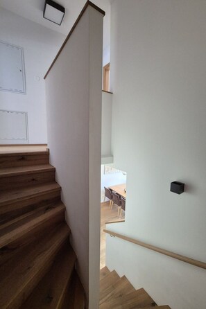 Eine Treppe mit Holzboden führt zu einer Essecke mit Tisch und Stühlen.