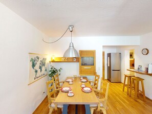 Eine kleine Küche mit Essbereich, Holzmöbeln, einer Pendelleuchte und einer Weltkarte an der Wand.