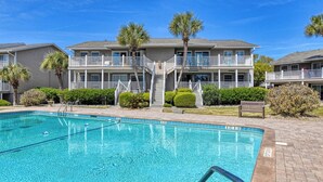 A swimming pool with a clear blue water, surrounded by a brick patio. - Floral Villa D14 - Three Bedroom Two Bath Condo with Shared Pool (Surfside Beach)