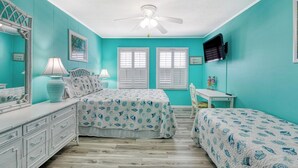 A bedroom with two beds, a ceiling fan, a TV, and a desk. - Floral Villa D14 - Three Bedroom Two Bath Condo with Shared Pool (Surfside Beach)
