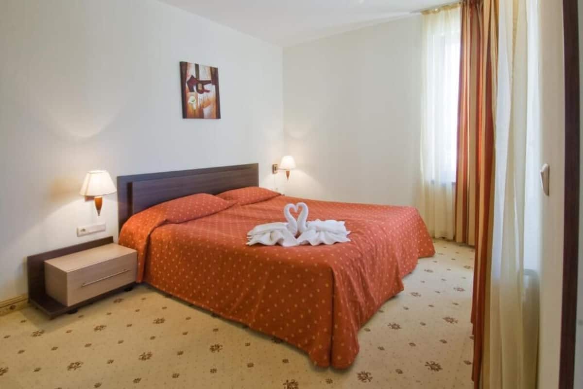 Une chambre d’hôtel avec un lit, une table de chevet, une lampe fixée au mur et un tableau.
