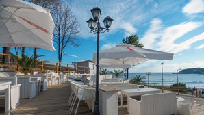 Une terrasse en bois avec des sièges d’extérieur blancs, un lampadaire et une vue sur la mer.
