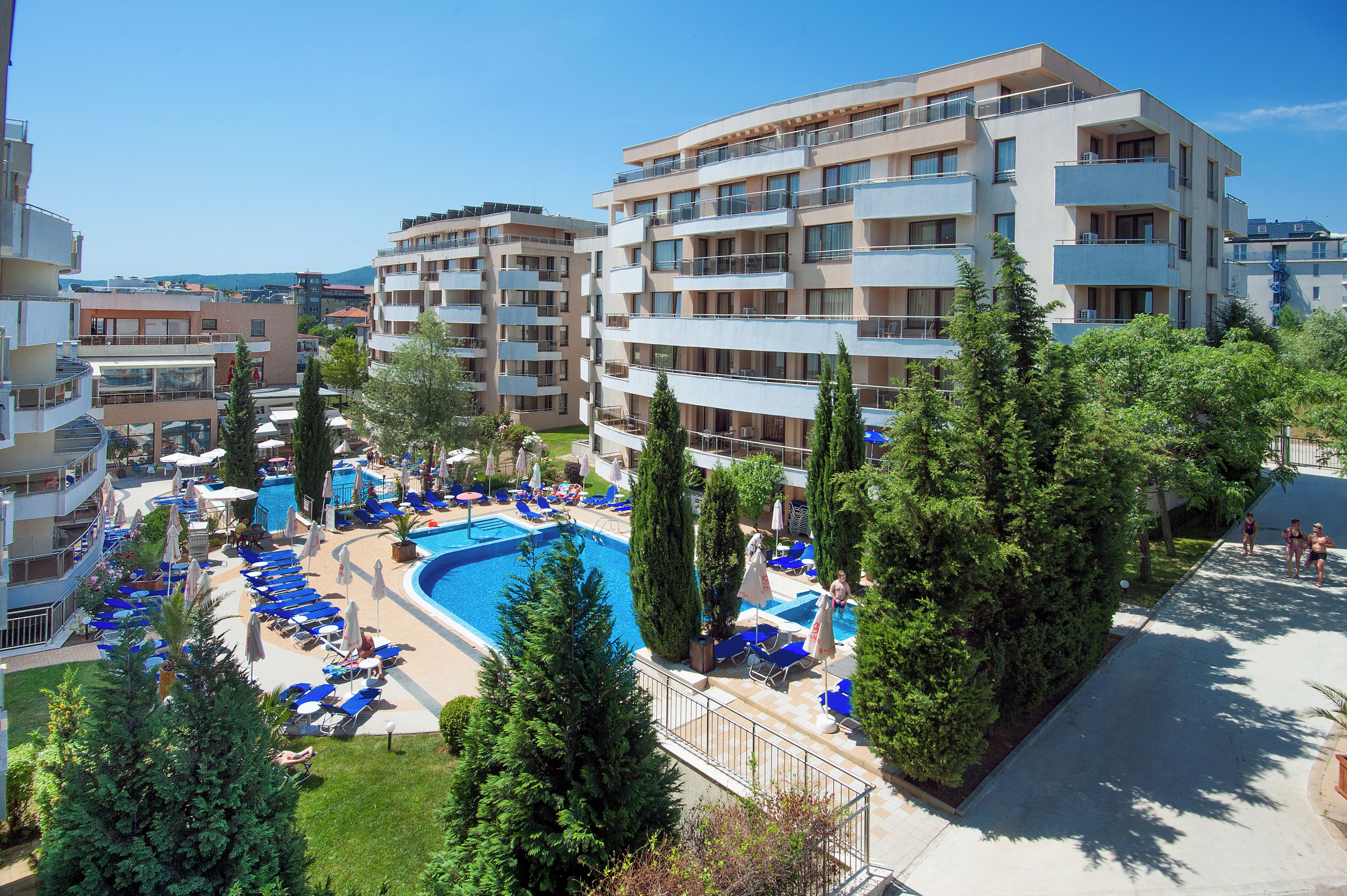 A hotel with a swimming pool, multiple balconies, and a clear view of the surrounding area.