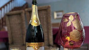 A bottle of champagne, several shot glasses, and a decorative glass on a table.