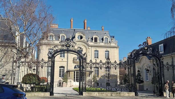 A historic building with ornate iron gates, a central archway, and a large entrance.