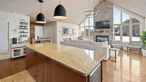 A modern kitchen with granite countertops, a large island, and a stone fireplace. - Waterfront with Spa - Pool Table - Le Rivage Alpin (Saint-Côme)