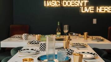 A dining table set with black and white patterned plates, gold cutlery, and a modern chandelier.